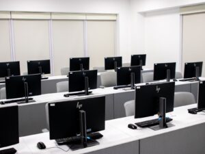 Spacious and minimalist computer lab with rows of black monitors and sleek furniture.