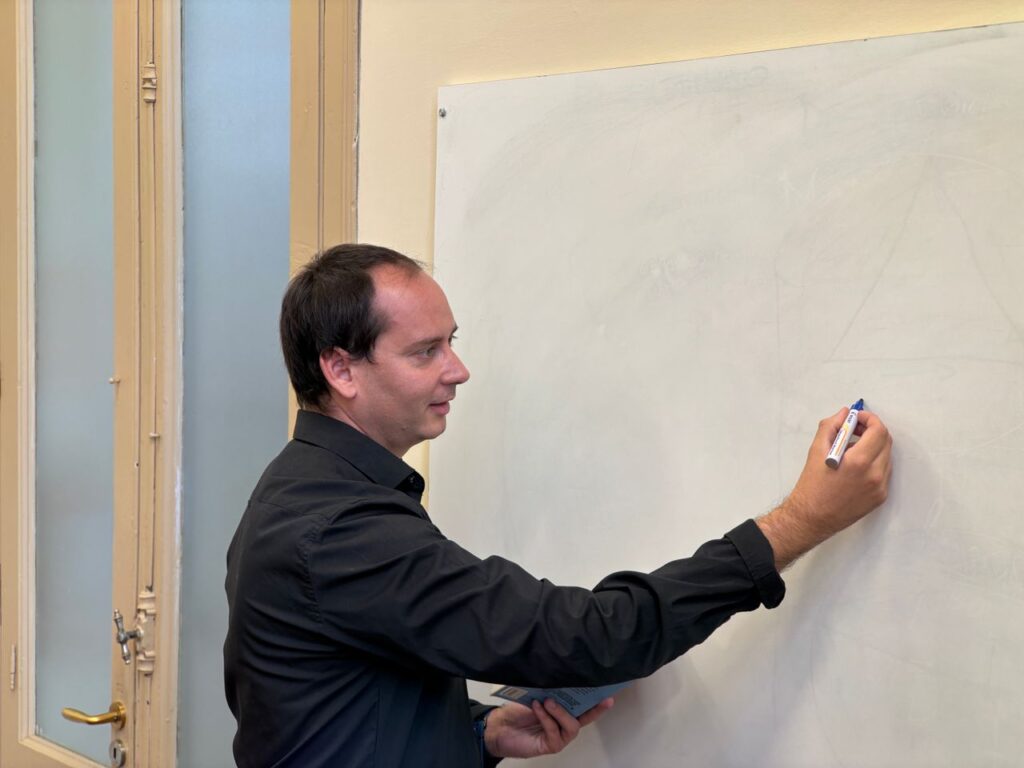 Formateur écrivant au tableau devant une salle de formation, illustration de la VAE de formateur pour adultes