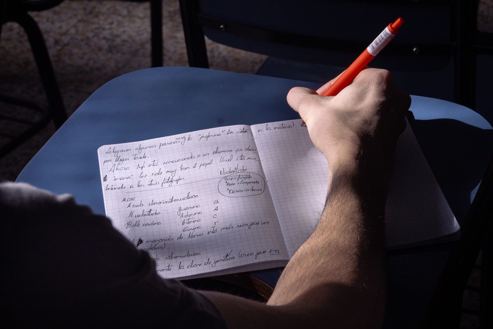 Adulte s'exerçant à l'écriture dans un cahier, cours d'alphabétisation
