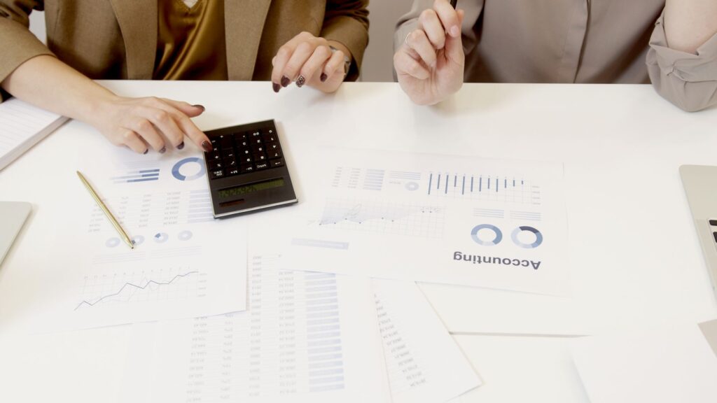 Deux professionnels examinent des documents financiers et comptables d un organisme de formation avec une calculatrice