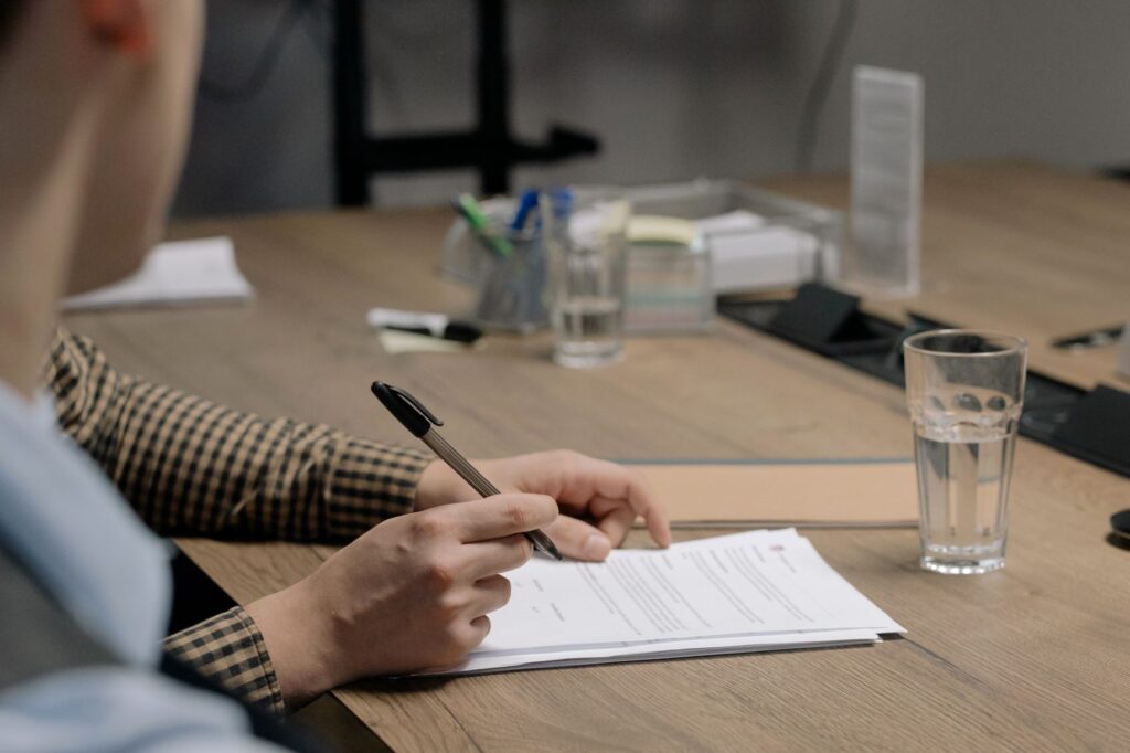 Professionnel signant un document dans un bureau, illustrant le cadre legal et reglementaire de la publicite dun organisme de formation