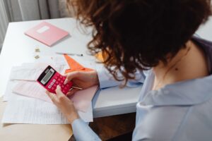 Gestionnaire estimant le budget de sa certification Qualiopi avec calculatrice et documents