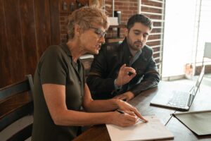 Formatrice accompagnant un apprenant adulte devant un ordinateur portable