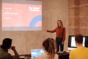 Formatrice animant une session sur l'intelligence artificielle devant un petit groupe, diapositive projetee